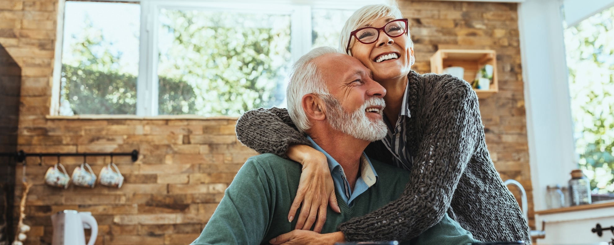 Senior couple hugging at table at home